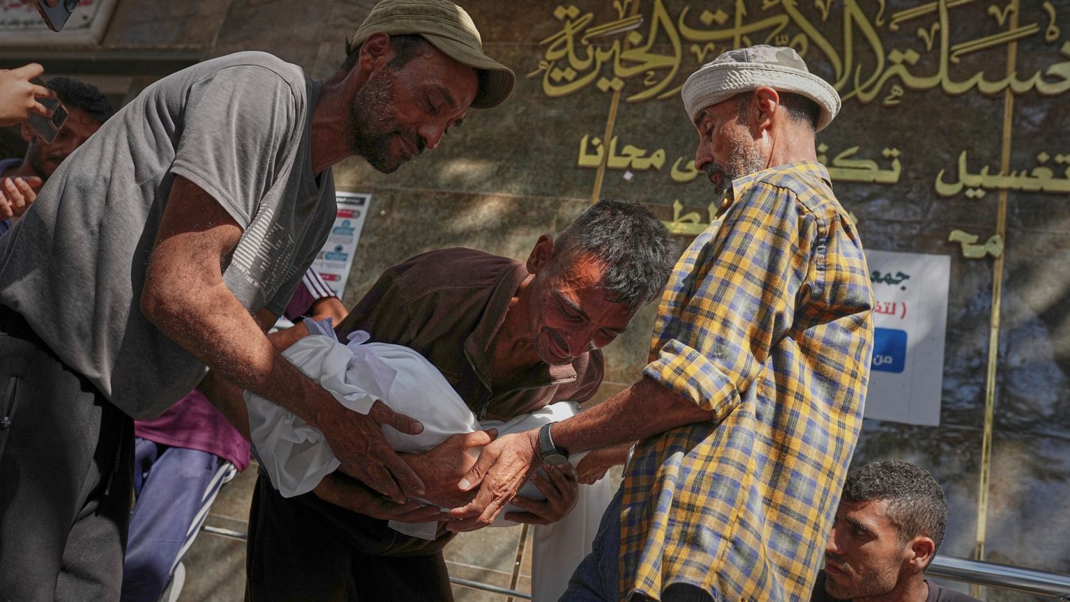 Un hombre lleva el cuerpo envuelto de un niño que presuntamente murió junto con otras personas en un ataque israelí dirigido contra una escuela en el norte de la Franja de Gaza.