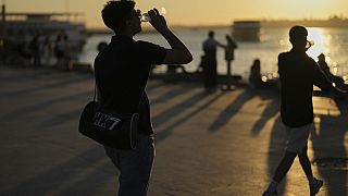 People drink water in a hot summer day at Kadikoy sea promenade, in Istanbul, Turkey, Wednesday, July 2, 2025.