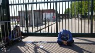 FILE: A man sits outside the gate of an overcrowded asylum seekers center where hundreds of migrants seek shelter in Ter Apel, 25 August 2021