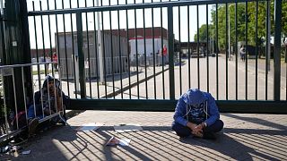 FILE: A man sits outside the gate of an overcrowded asylum seekers center where hundreds of migrants seek shelter in Ter Apel, 25 August 2021