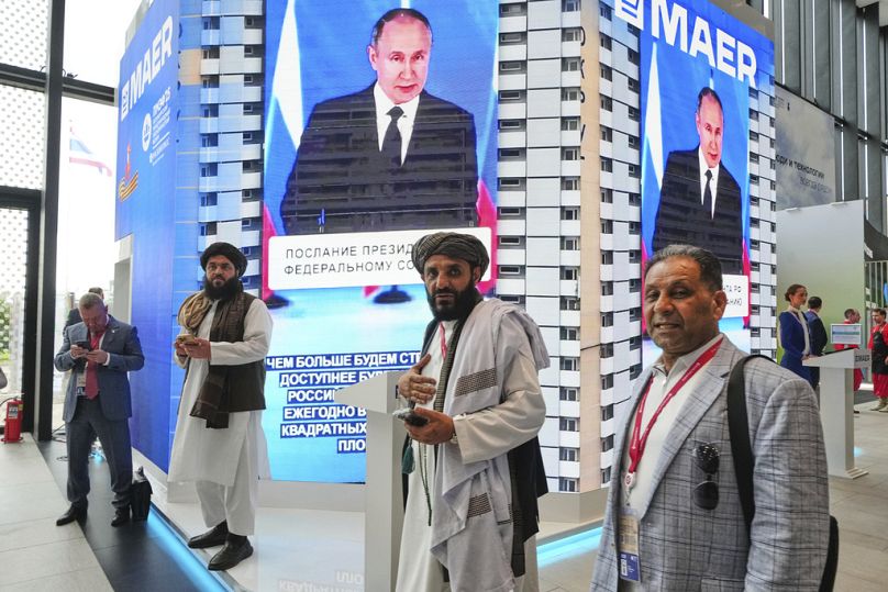 Des membres des talibans se tiennent devant des écrans de télévision alors qu'ils assistent au Forum économique international de Saint-Pétersbourg, en Russie, le 18 juin 2025.