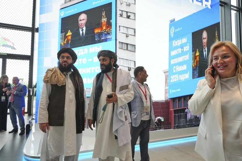 Des membres des talibans se tiennent devant des écrans de télévision alors qu'ils assistent au Forum économique international de Saint-Pétersbourg, en Russie, le 18 juin 2025.