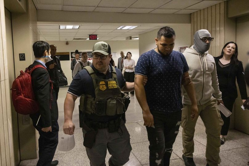Des agents de la patrouille frontalière retiennent une personne à l'extérieur d'une salle d'audience du tribunal de l'immigration à New York, mardi 10 juin 2025.