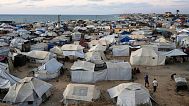 Palestinians displaced by the Israeli air and ground offensive on the Gaza Strip, stand in an area at a makeshift tent camp at dusk in Khan Younis, Gaza Strip, Wednesday