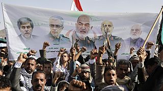 Houthi supporters chant slogans as they raise a banner showing Iranian leaders who were killed during Israeli strikes in Sanaa, Yemen, Friday, June 13, 2025.