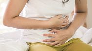 A woman clutches her stomach in pain.
