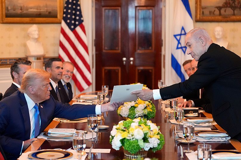 Israeli Prime Minister Benjamin Netanyahu hands a folder to U.S. President Donald Trump during a meeting at the White House in July 2025.