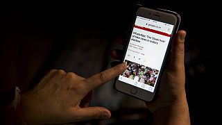 A woman reads an article on her mobile phone concerning the chances of fake news.