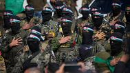 Hamas fighters stand in formation ahead of a ceremony to hand over Israeli hostages to the Red Cross in Nuseirat, 22 February, 2025