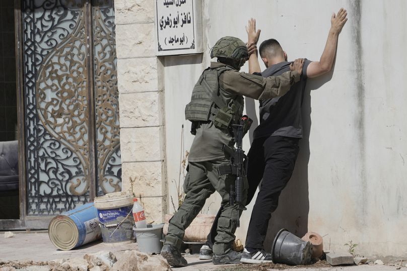 جندي إسرائيلي يفتش جسديًا فلسطينيًا في مخيم طولكرم للاجئين، في 6 تموز/ يوليو 2025.