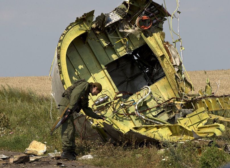 Um rebelde pró-russo toca nos destroços do MH17 no local da queda do voo 17 da Malaysia Airlines, perto da aldeia de Hrabove, no leste da Ucrânia, a 22 de julho de 2014