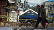 Residents walk past rubble that fell from a home that was damaged after dozens of earthquakes and aftershocks were recorded in a matter of hours in Palín, 9 July, 2025