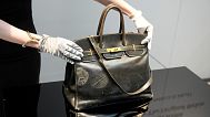 An auction officer displays the original Birkin bag created by Hermès for Jane Birkin in 1984, prior to its auction Thursday, July 10, 2025 in Paris.