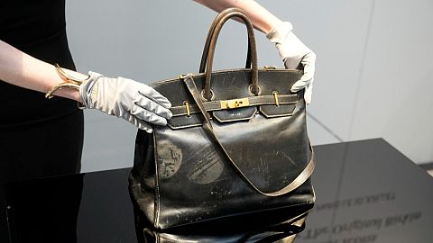 An auction officer displays the original Birkin bag created by Hermès for Jane Birkin in 1984, prior to its auction Thursday, July 10, 2025 in Paris.