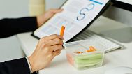 A woman eats a snack at work.