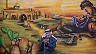  یک پناهنده فلسطینی در روز چهارشنبه ۱۸ ژوئن ۲۰۱۴ با دیواری تزئین شده با نقاشی دیواری که درگیری اسرائیل و فلسطینی را نشان می دهد 