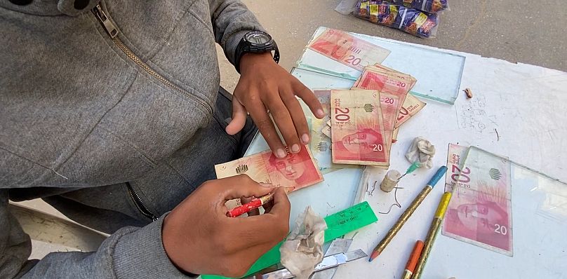 عامل تصليح عملة يعرض ورقات تالفة أثناء تصليحها