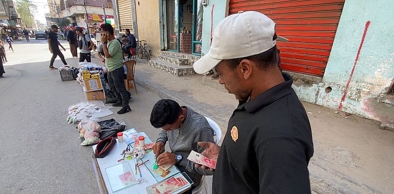 عمال تصليح عملة يعملون على تصليح الأوراق النقدية في غزة