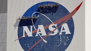 Workers on scaffolding repaint the NASA logo near the top of the Vehicle Assembly Building at the Kennedy Space Center in Cape Canaveral, Florida.