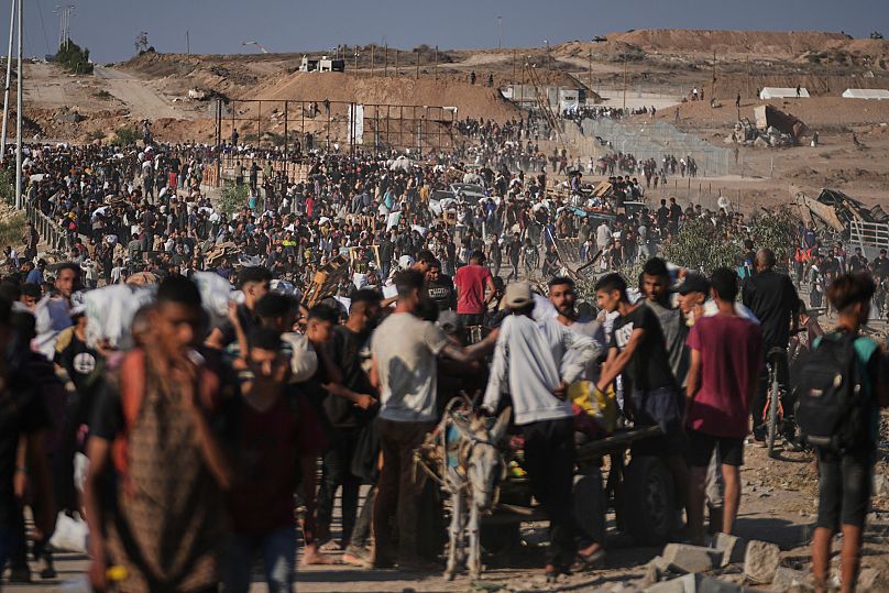 Palestinians carry humanitarian aid packages near a GHF distribution centre in Khan Younis, 26 June, 2025