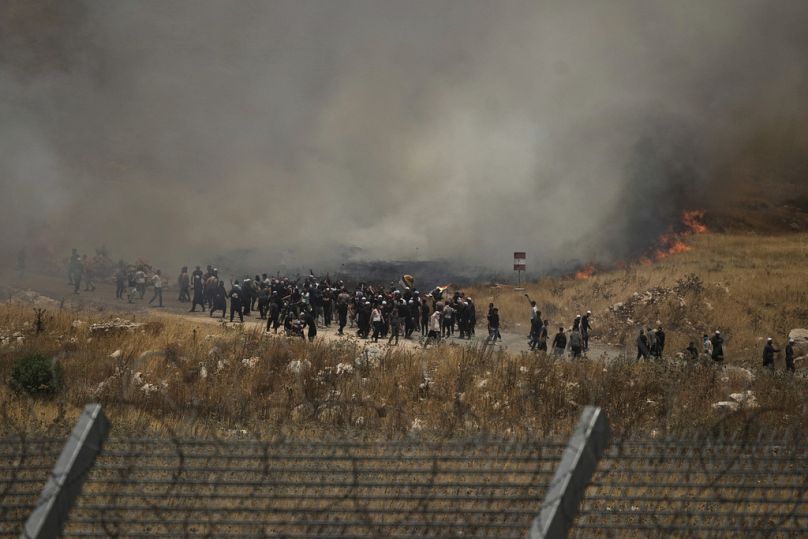 دروز سوريون يحتجون على الجانب السوري من الحدود مع إسرائيل، كما يُرى من مجدل شمس في الجولان المحتل، الأربعاء 16 يوليو 2025.  