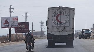 مقاتلون يركبون دراجة نارية أمام قافلة من المركبات محملة بالمواد الغذائية والمساعدات الأخرى في طريقهم إلى السويداء على الطريق السريع الدولي في ريف درعا ، سوريا ، الأحد 20 يوليو