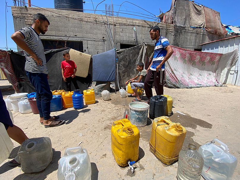 فلسطينيون في دير البلح ينتظرون تعبئة أوعيتهم البلاستيكية بالماء بتاريخ 19 تموز 2015