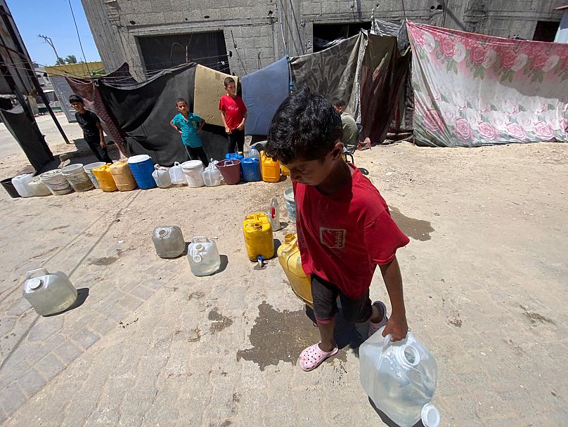 طفل من دير البلح في قطاع غزة ينجح في الحصول على بعض الماء لعائلته، السبت 19 تموز/ يوليو 2025.
