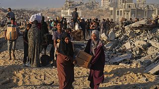 فلسطينيون يحملون أكياسا وصناديق مساعدات غذائية وإنسانية تم تفريغها من قافلة تابعة لبرنامج الأغذية العالمي كانت متوجهة إلى مدينة غزة ، شمال قطاع غزة ، الاثنين 16 حزيران / يونيو