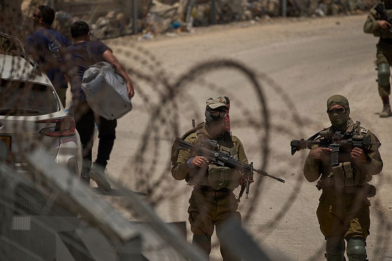 Unos soldados israelíes hacen guardia mientras los drusos sirios cruzan de regreso a Siria en su frontera con Israel, el 17 de julio de 2025.