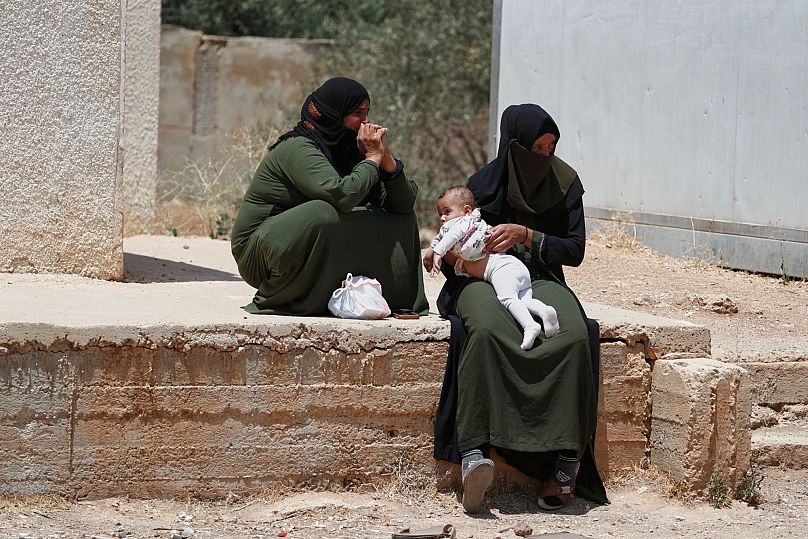 Unas beduinas desplazadas se sientan afuera de un refugio que alberga a sus familias en la ciudad de Nahtah, 21 de julio de 2025.
