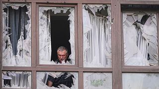 مردی پس از حمله روسیه در کی‌یف، اوکراین، دوشنبه، ۲۱ ژوئیه ۲۰۲۵، کنار پنجره‌های شکسته خانه‌اش ایستاده است.