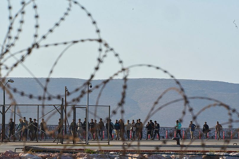 Migrants rescued south of Crete after making the journey from Libya walk after their arrival at the port of Lavrio, 10 July, 2025