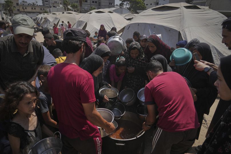فلسطينيون نازحون يتلقّون وجبات غذائية في مطبخ مجتمعي بمدينة غزة، شمال قطاع غزة، الثلاثاء 22 يوليو 2025.     
