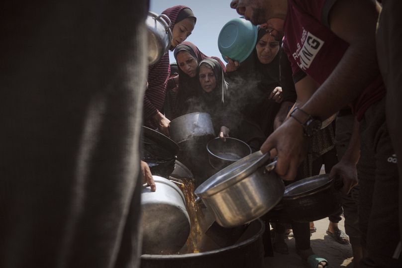فلسطينيون نازحون يتلقون طعامًا مقدمًا في مطبخ جماعي بمدينة غزة، شمال القطاع، الثلاثاء 22 يوليو 2025.