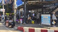 People sit near a border checkpoint between Thailand and Cambodia in Sa Kaeo Province, 24 June, 2025