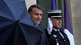 French President Emmanuel Macron holds an umbrella at the Elysee Palace in Paris, 24 July 2025 