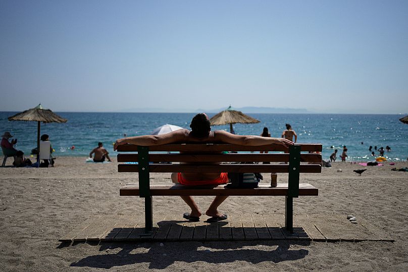 Un uomo prende il sole seduto su una panchina durante un'ondata di caldo nella spiaggia pubblica di Paleo Faliro, nel sud di Atene, Grecia, 21 luglio 2025