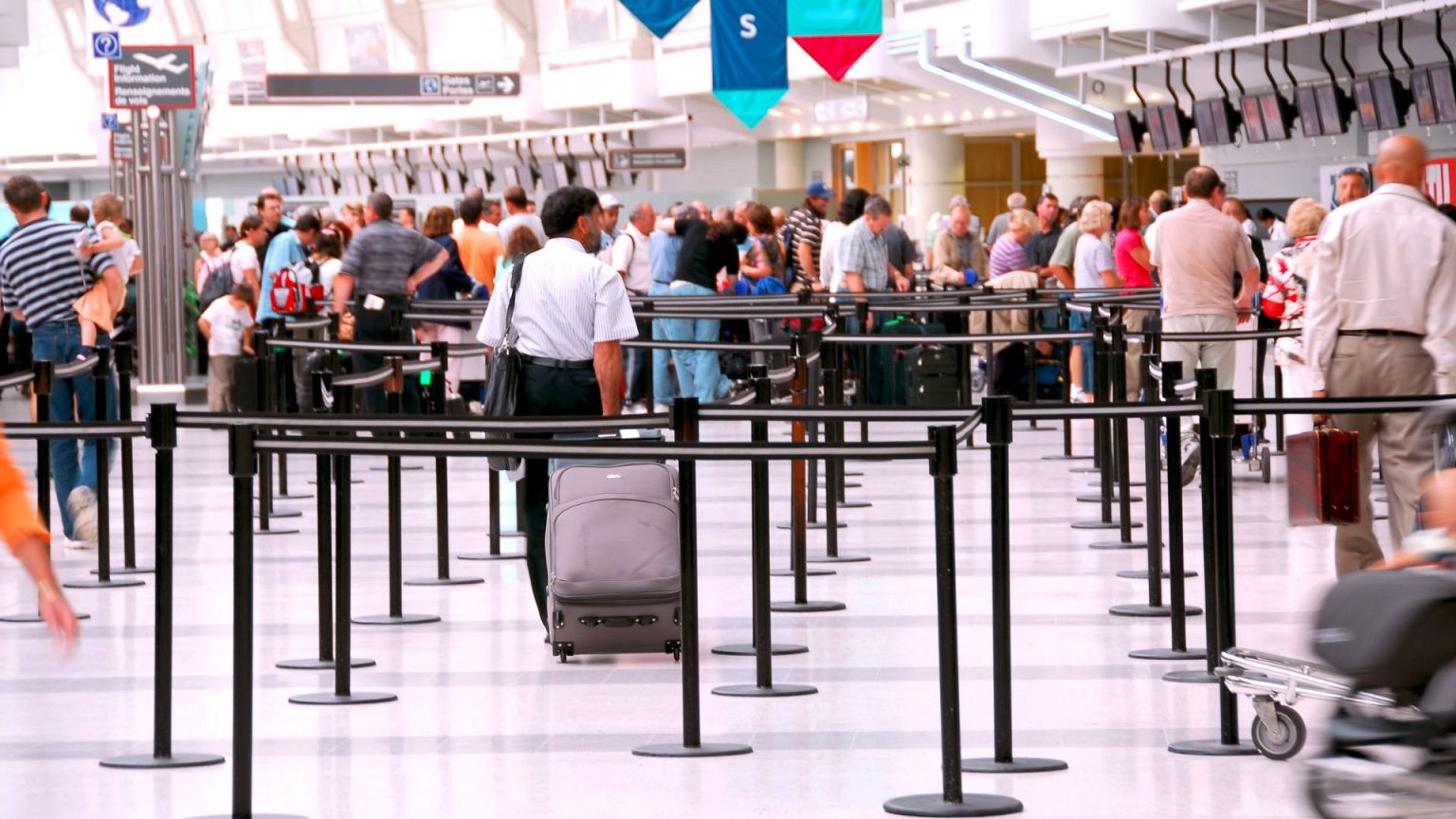 Passengers waiting in line at check-in counters in an airport. 