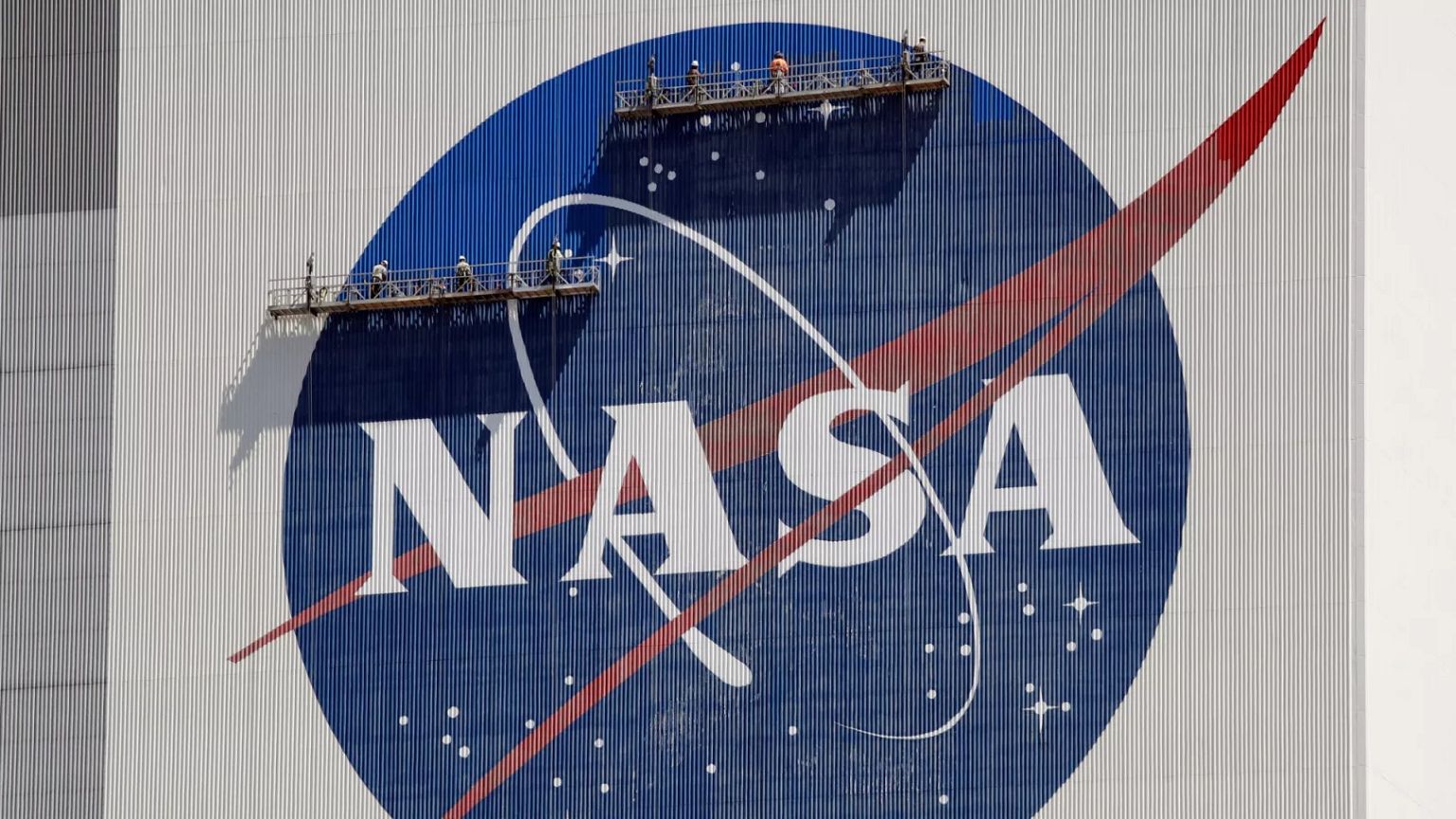 FILE - Workers on scaffolding repaint the NASA logo near the top of the Vehicle Assembly Building at the Kennedy Space Center in Cape Canaveral, Fla., May 20, 2020. (AP Photo/