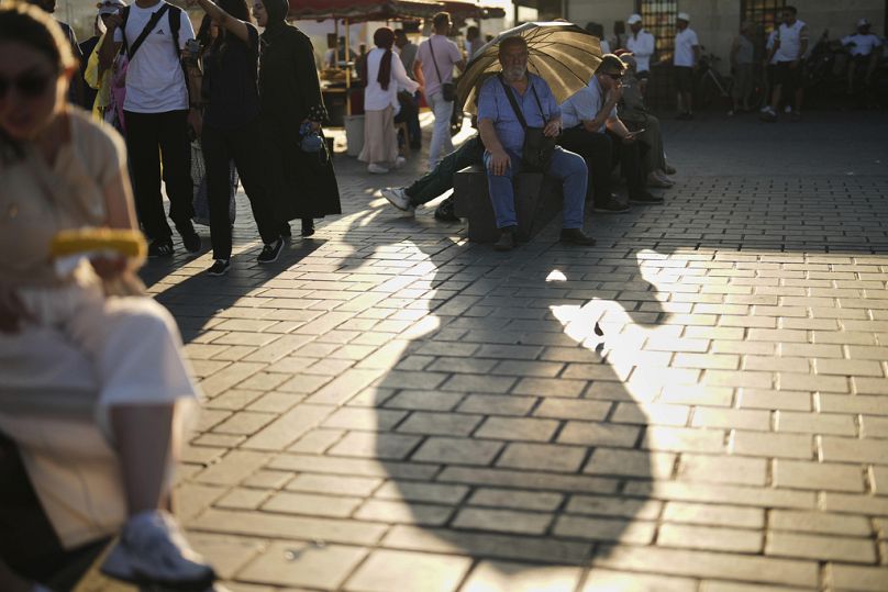 Um homem protege-se do sol com um guarda-chuva num dia quente de verão em Istambul, terça-feira, 8 de julho de 2025.