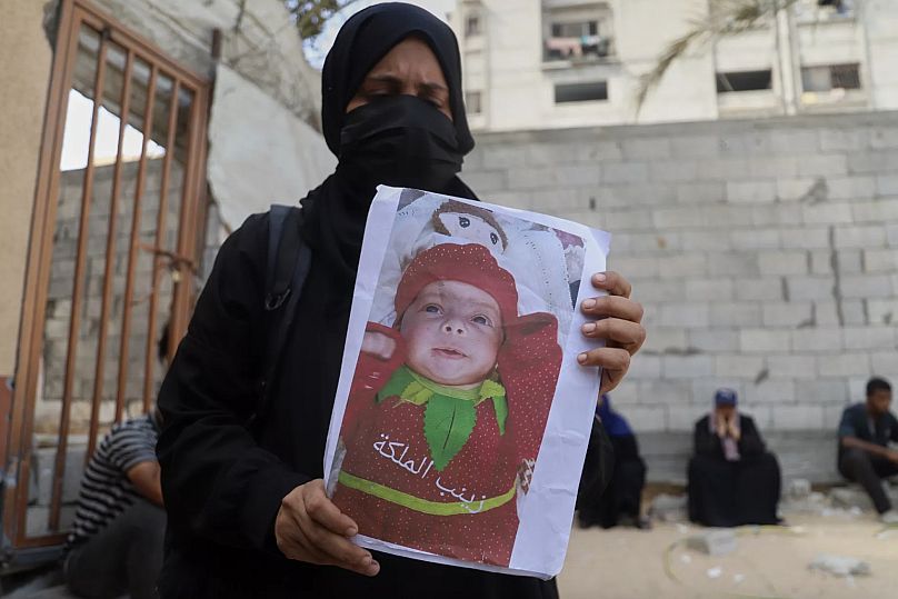 Esraa Abu Halib, ailesine ve hastaneye göre yetersiz beslenmeye bağlı nedenlerden ölen 5 aylık bebeği Zainab'ın fotoğrafını gazetecilere gösteriyor.