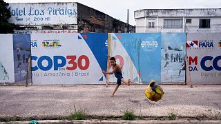  A boy kicks a soccer ball near signage for COP30 in Belem, Brazil.