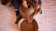 A woman pours argan nuts to extract oil at a cooperative in Essaouira, Morocco.