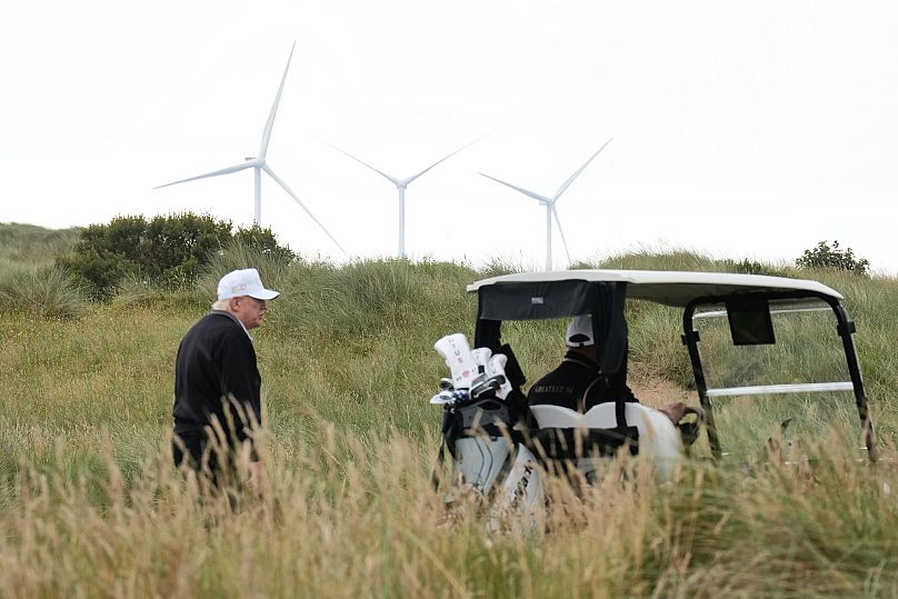 President Donald Trump walks backdropped by wind turbines during an opening ceremony for the Trump International Golf Links golf course, near Aberdeen, Scotland, July 29, 2025