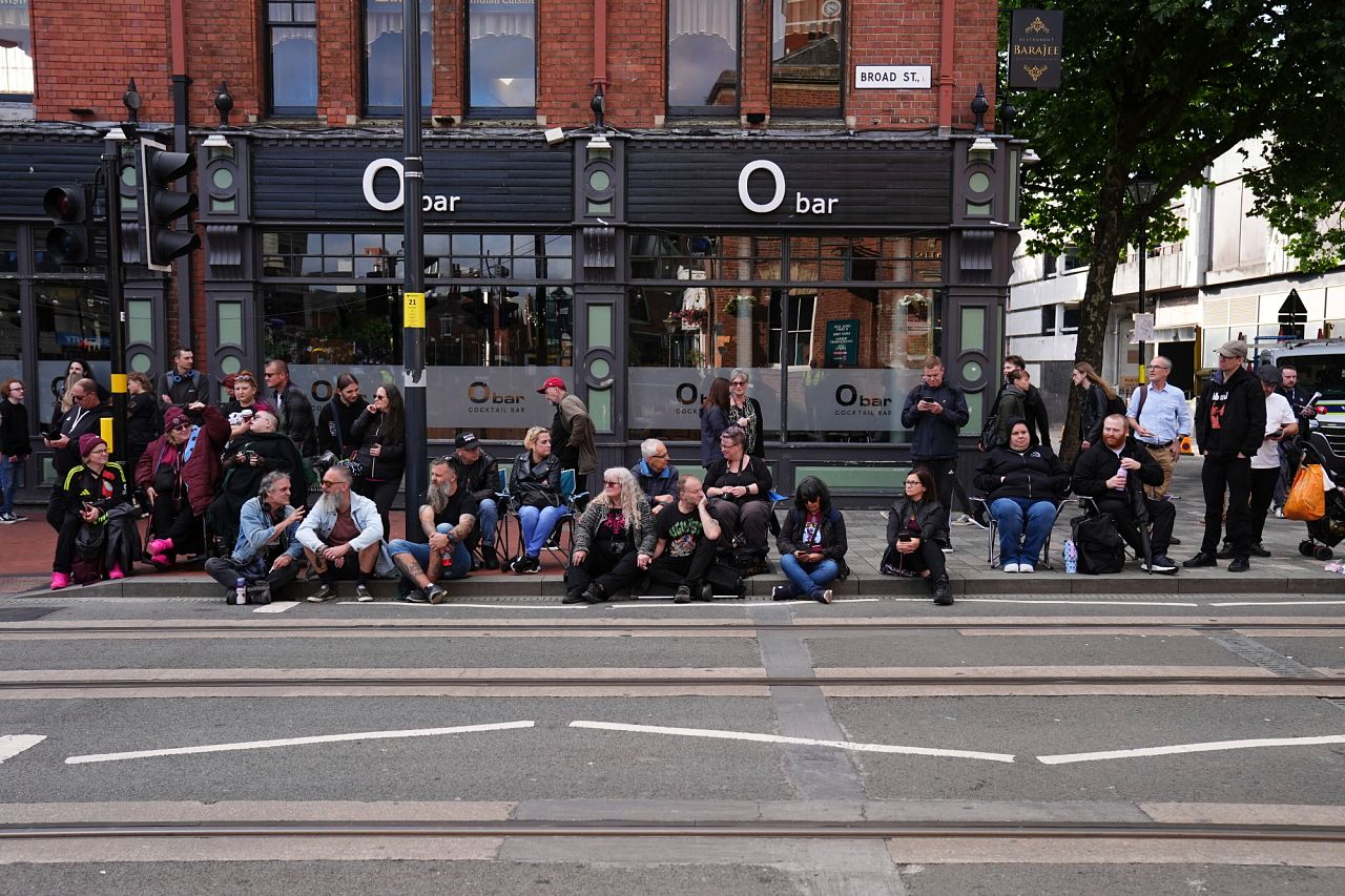 Fans gather near the Black Sabbath Bridge bench on Broad Street ahead of the funeral procession