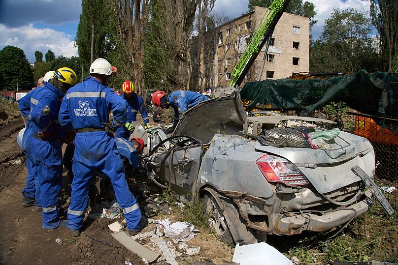 Emergency workers inspect a damaged car close to the multi-storey residential house that was ruined by a Russian missile in Kyiv, 1 August, 2025