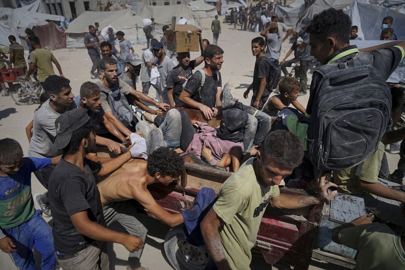 Palestinians are carried after being wounded while trying to reach trucks carrying humanitarian aid en route to Gaza City, in the outskirts of Beit Lahiya, northern Gaza Strip