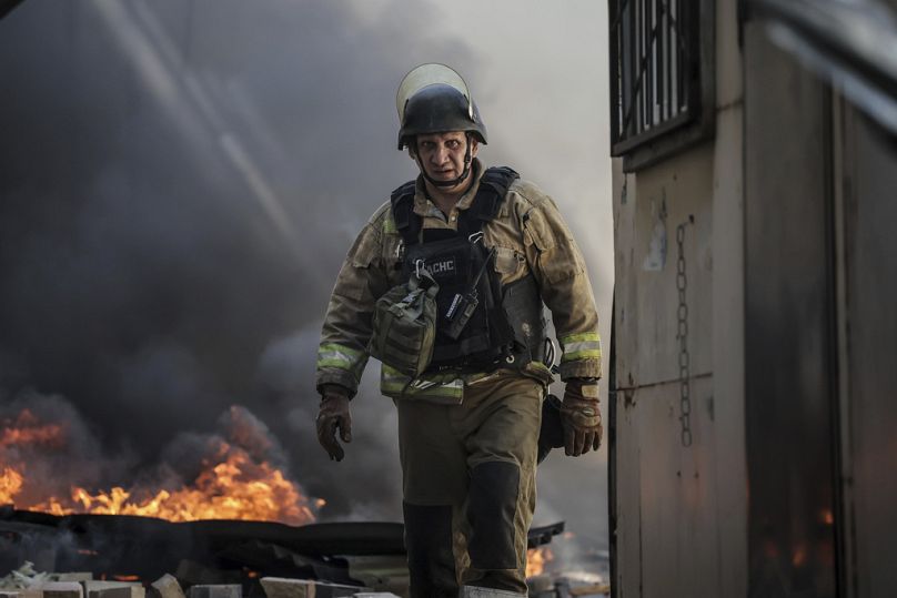 En esta foto facilitada por el servicio de prensa de la 24ª Brigada Mecanizada de Ucrania, un bombero apaga el fuego tras el impacto de un dron ruso en el mercado