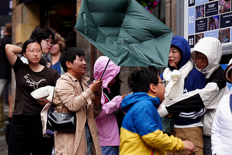 Members of the public battle against the wind as they walk along the Royal Mile in Edinburgh, 4 August, 2025